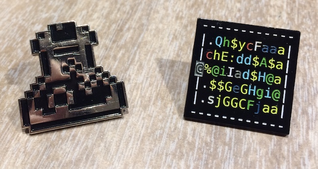 Two small metal pins: a pixelly potion bottle and a Nethack treasure zoo